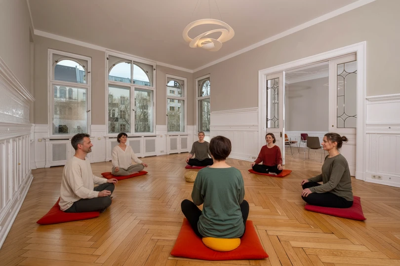 mehrere Personen sitzen im Rahmen einer Entspannungstherapie zusammen