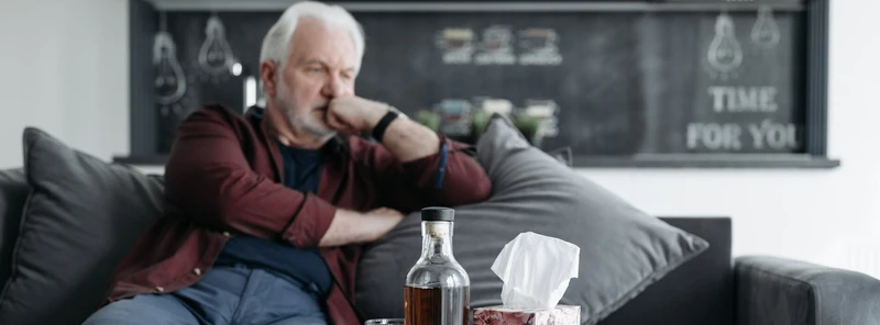 Mann sitzt vor einer Alkoholflasche